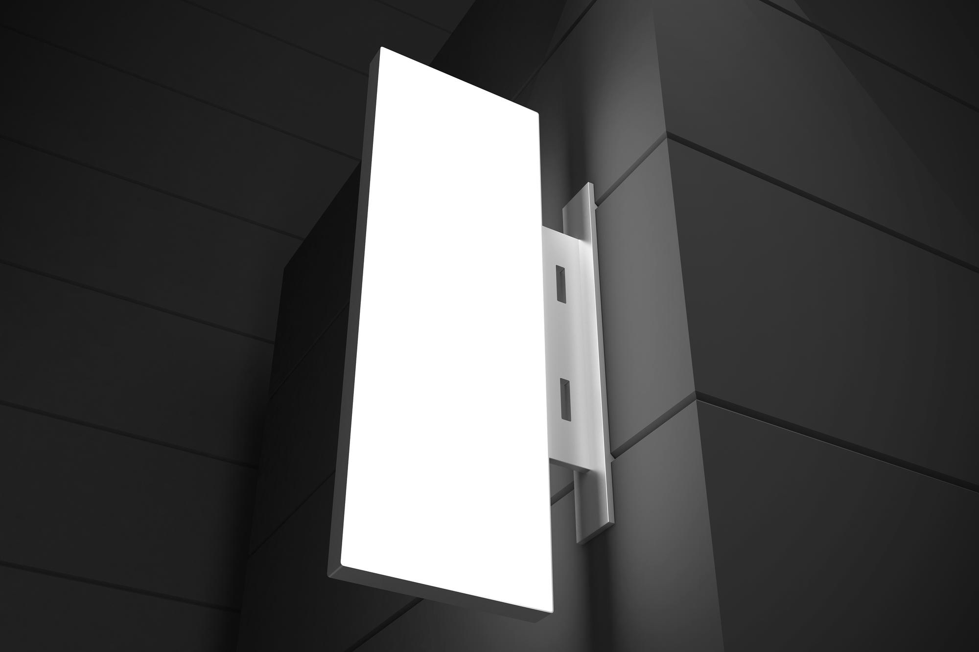 cajas de luz rectangulares Caja de luz vertical y rectangular con iluminación LED uniforme, instalada mediante un soporte metálico en una esquina de fachada moderna y minimalista.